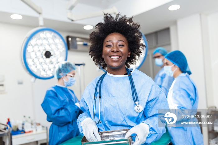 Portrait of smiling African American female surgeon in surgical uniform taking surgical instruments 