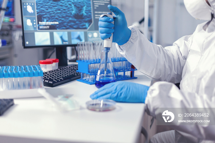 专业实验室科学家穿着防护服，用自动移液管滴下样本。化学