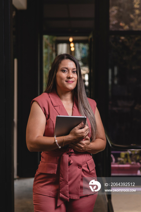 Retrato de una bella mujer latina con una tableta digital en sus manos mirando a la cámara