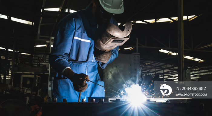 Industrial worker welding metal with many sharp sparks