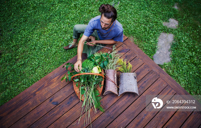 High angle view of man arranging leaves in basket while sitting on grassy field