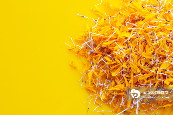 Petals of marigold flower on yellow background.