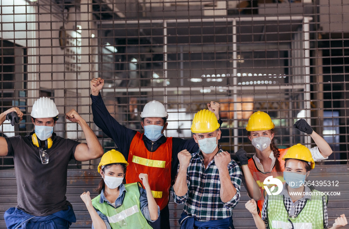 Happy group of industrial worker wearing protective face mask celebrating after factory reopen at co