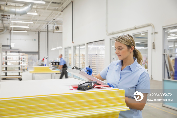 Worker writing on clipboard in factory