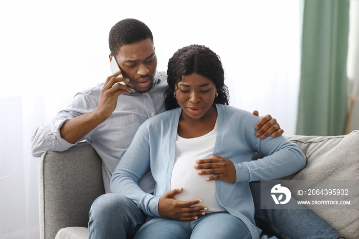 Worried black man calling doctor while wife having labor pains