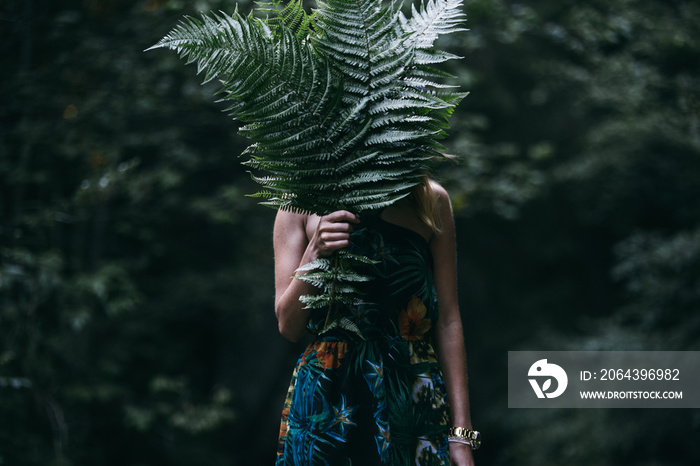 幸福的年轻女人，手里拿着蕨类植物的叶子在森林里