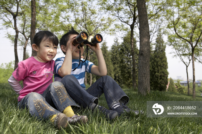 小女孩和小男孩用望远镜看远方