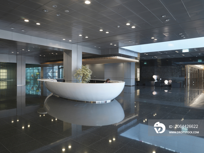 Luxurious hotel reception lobby area with recessed lights reflecting on floor