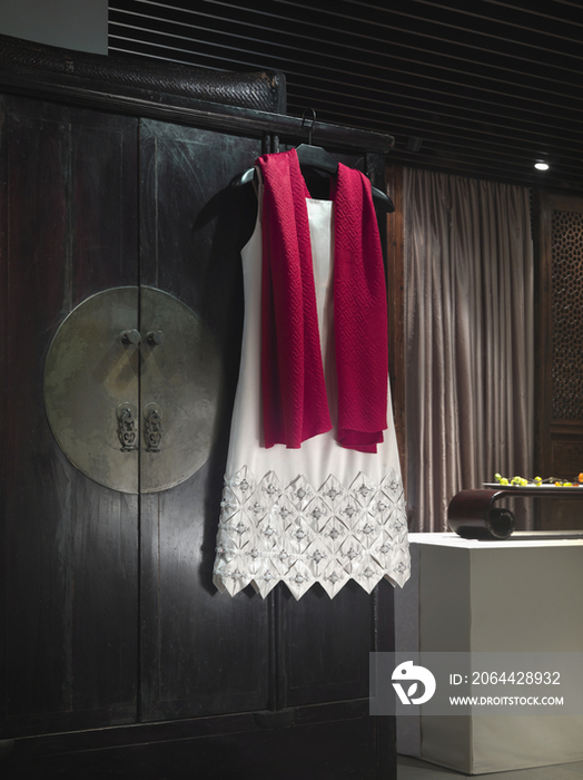 Elegant dress and scarf on coat hanger in house