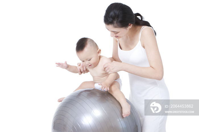 母亲指导婴儿在健身球上玩