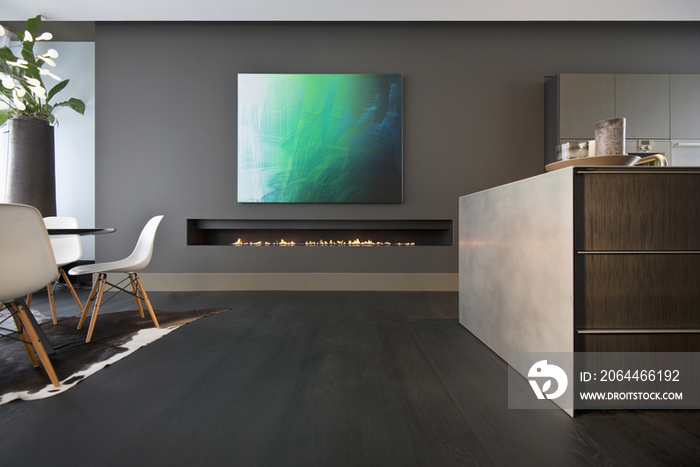 Interior shot of cropped dining table with painting over modern fireplace at home