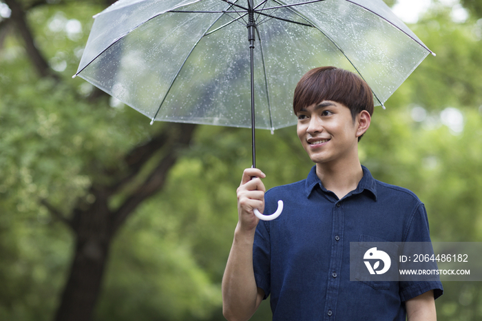 快乐的年轻男子打着雨伞