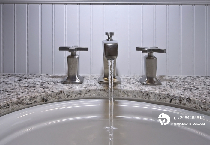 Close-up of faucets and running water in bathroom