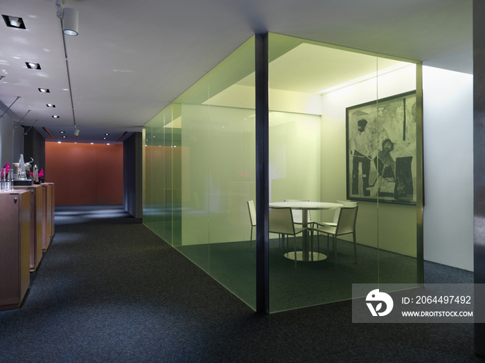 Chairs surrounding circular table in glass cabinet of modern office