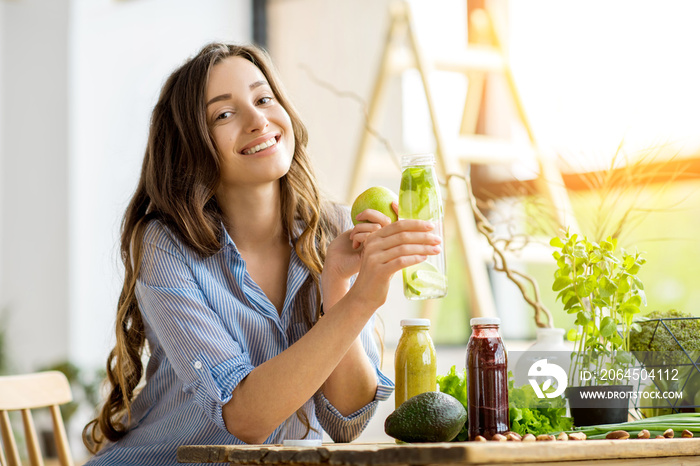 美丽快乐的女人坐在家里喝着饮料和健康的绿色食品。素食餐和排毒conco