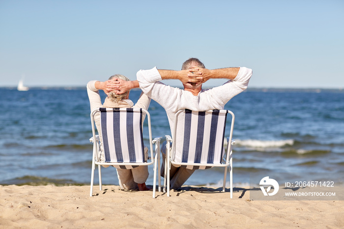 一对老年夫妇坐在夏日海滩的椅子上