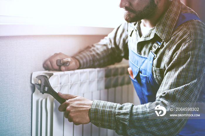 service man with wrench near radiator