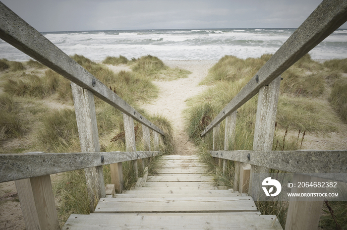 Wooden steps leading down through the dunes onto the shingle beach in winter