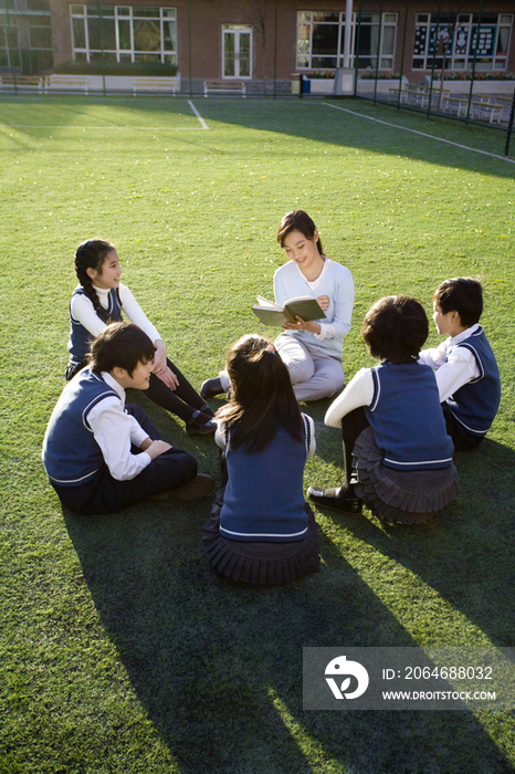 小学生在草地上围着老师学习