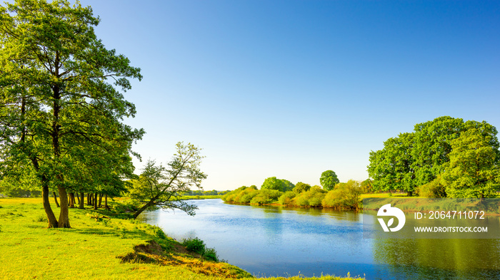 Sommerliche Landschaft mit Wiesen und Fluss