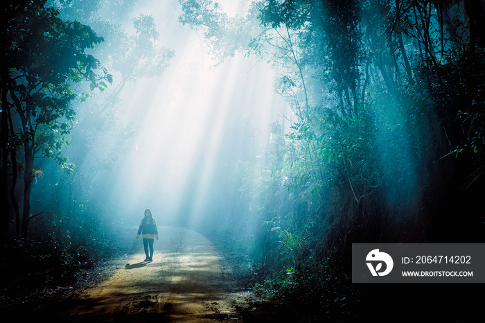 Girl in sun rays coming through the trees in forest