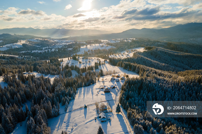 冬季空中景观，寒冷山区白雪皑皑的森林之间有小村庄的房屋