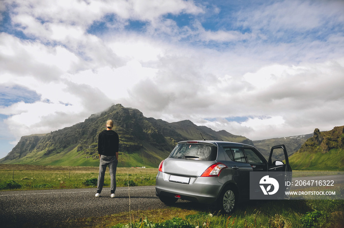 Man standing next to his car in the mountains