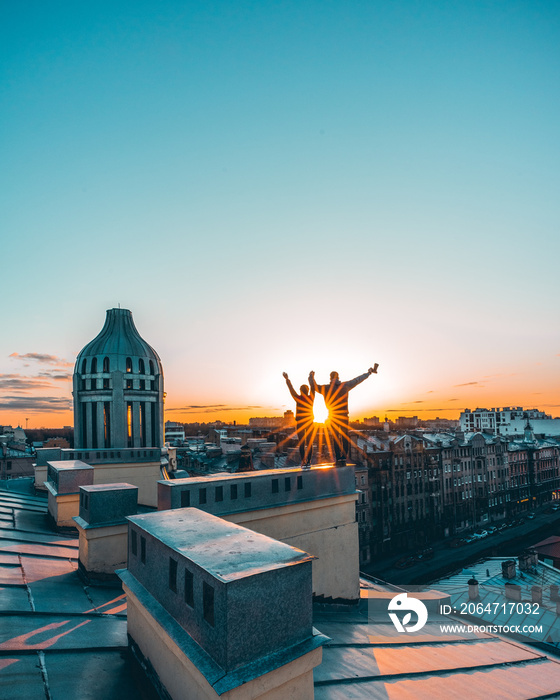 couple silhouettes stay on the rooftop in lights of sunset in historical city center of Saint-Peters