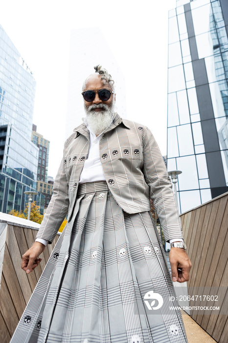 gray hair bearded man wearing skirt suit in modern city location