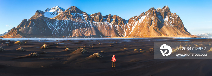 Hiker enjoying sunset at Vestrahorn and its black sand beach in Iceland