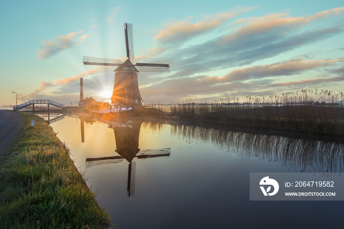 The De Kaagmolen windmill in front of a channel and boat, North Holland, Netherlands