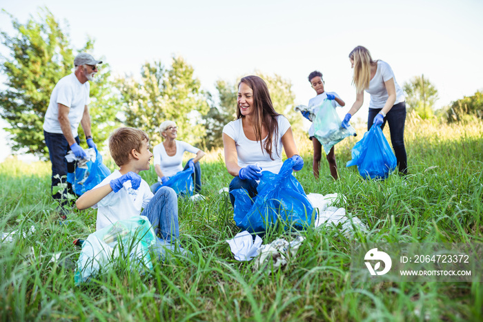 Volunteers with garbage bags cleaning up garbage outdoors - ecology concept.