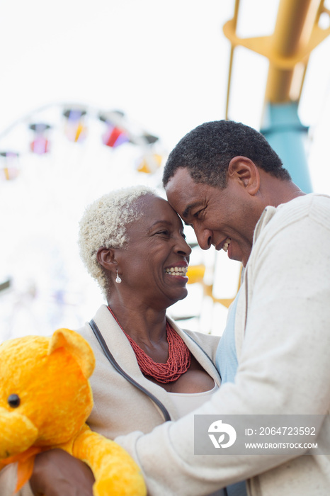 Happy senior couple with teddy bear at amusement park