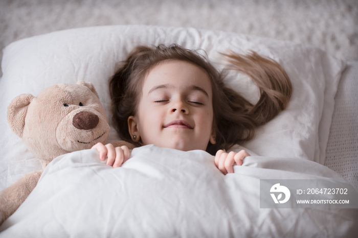 Little cute girl in bed with toy