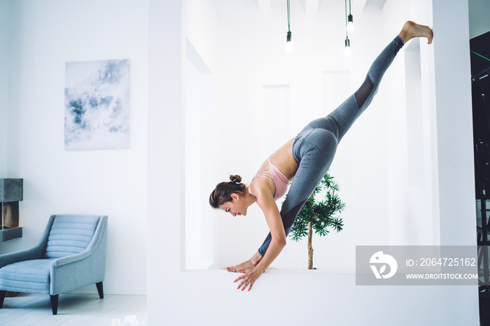 Flexible woman doing yoga in spacious room