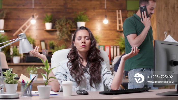 Relaxed zen businesswoman with closed eyes sitting at desk in yoga position meditating during work p