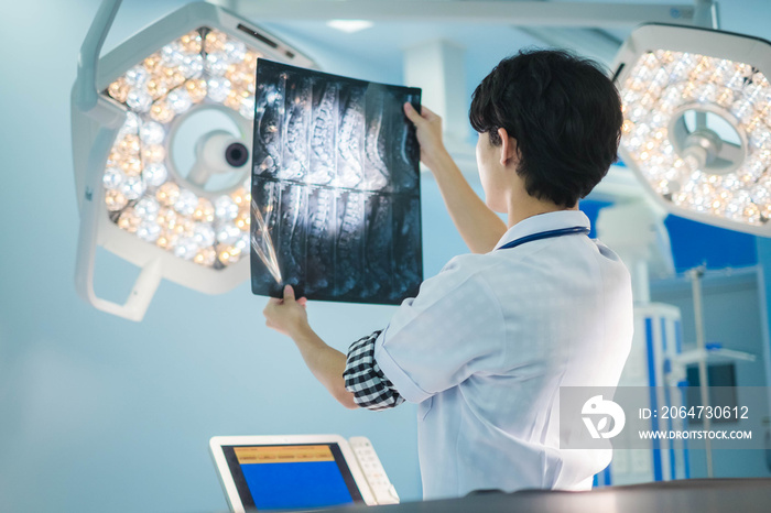 Surgical doctor looking at radiological spinal x-ray film for medical diagnosis on patient’s health 