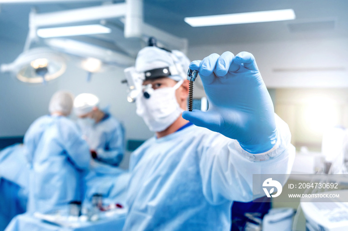脊柱手术。外科医生在手术室展示带手术设备的多轴螺钉。椎板切除术。