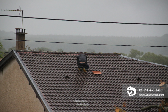 Man replacing roof tile during a storm