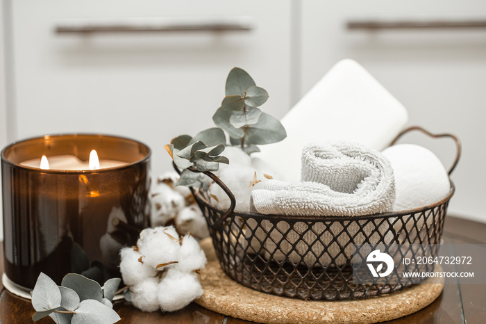 Spa composition with a burning candle and bath accessories.