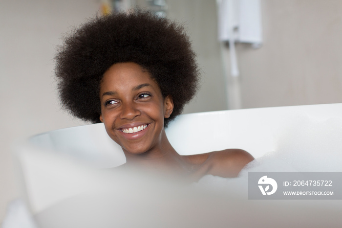 Happy young woman with afro enjoying bubble bath