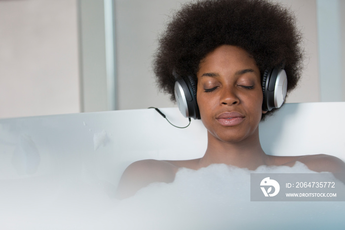 冷静的非洲裔年轻女子在洗澡时戴着耳机听音乐