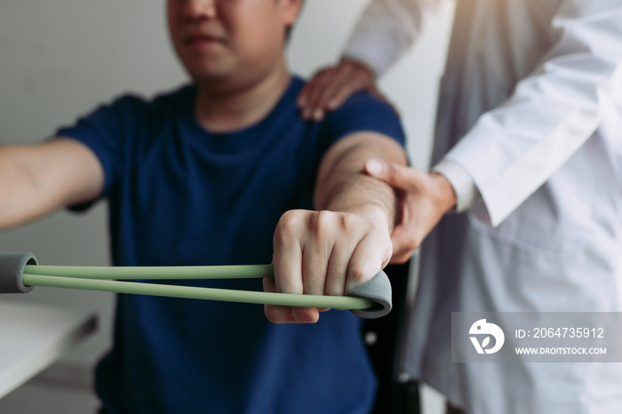 Asian male physical therapist descent working with patient doing stretching exercise with a flexible