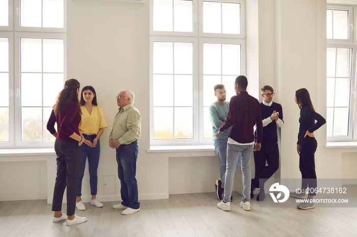 Diverse people mingling in community meeting or group therapy, talking about common interests, getti