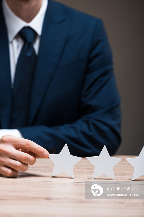 cropped view of man in formal wear touching star isolated on grey, quality concept