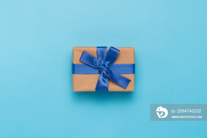 Gift box with blue ribbon on a blue background. Holiday, birthday, a gift to your loved one. Flat la