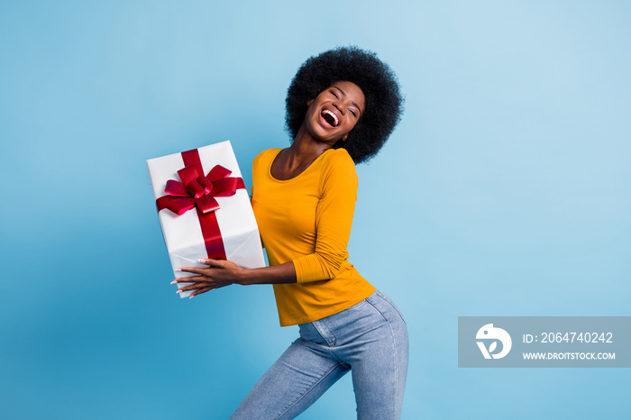 Photo portrait of happy smiling black skinned woman keeping wrapped gift laughing dancing isolated o