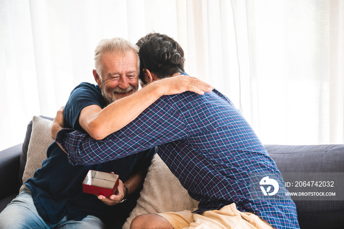 Son make a birthday surpised congratulate to elderly happy father with a gift box and hug