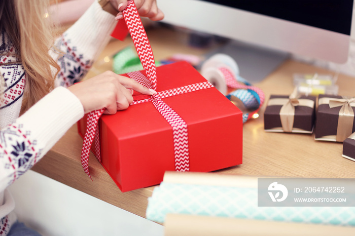 Adult woman at home wrapping Christmas presents