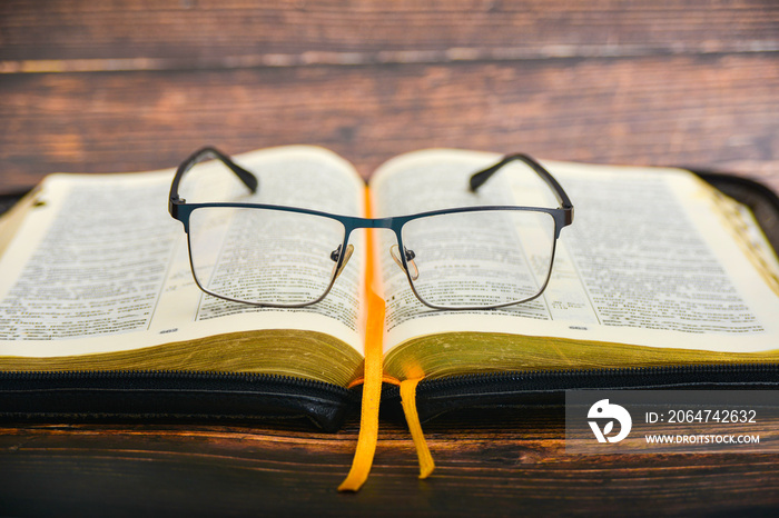 The Bible and glasses, glasses for sight lie on the opened Bible of a gift issue with gilded pages.